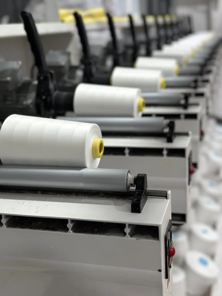 White thread cones on winding equipment, supplied factory photograph